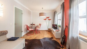 A modern living room with a sofa, a dining table with chairs, a TV, and a guitar. - Wohnen im Herzen der Altstadt (Würzburg)