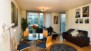 A modern living room with a glass dining table, wooden chairs, a dark sofa, and a black rug. - The Hub - Milton Keynes - Instagram Heaven (Milton Keynes)