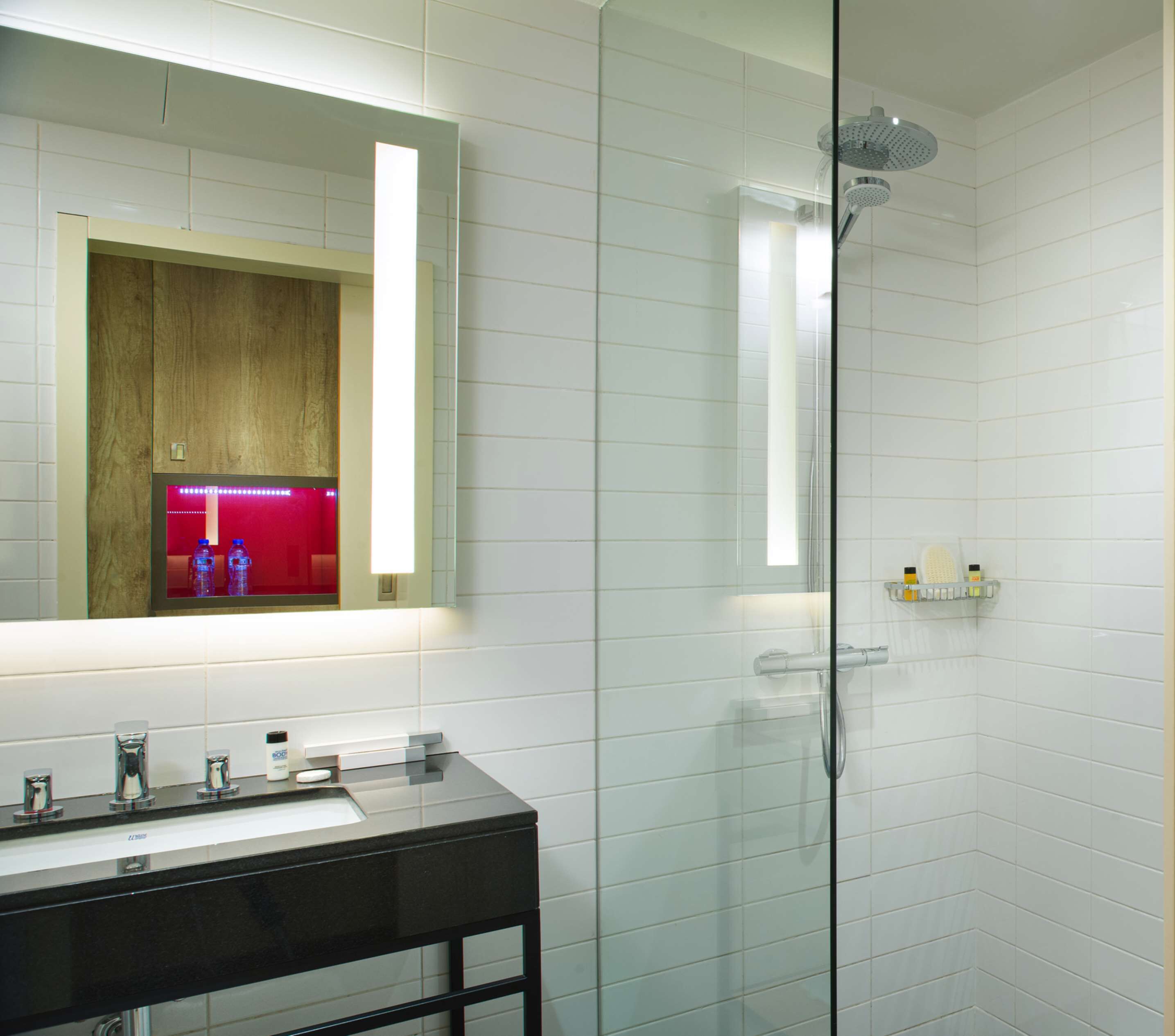 A modern bathroom with a glass shower enclosure, a vanity with a sink, and a mirror above it.