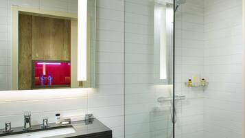 A modern bathroom with a glass shower enclosure, a vanity with a sink, and a mirror above it.
