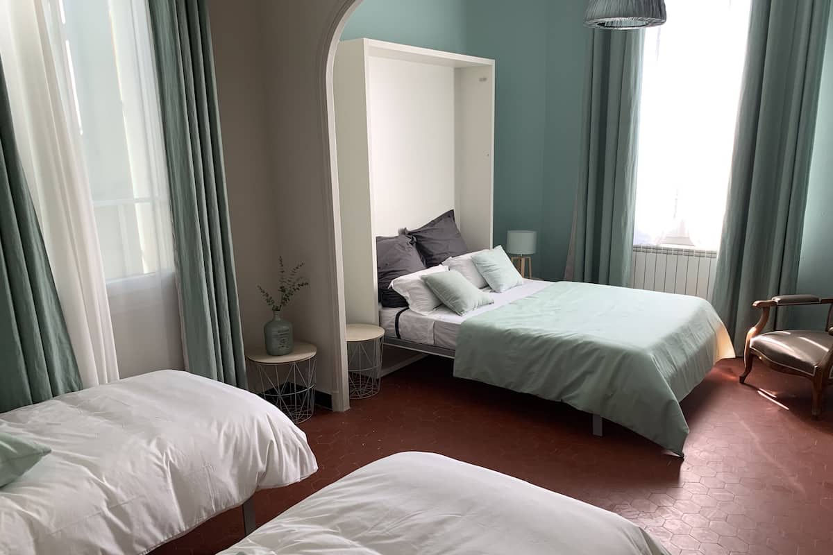A hotel room with two beds, a sitting area, and a window with curtains.