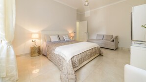 A bedroom with a bed, a bedside table with a lamp, a sofa, and a wardrobe.