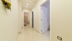 A hallway with a white door, a wall-mounted light fixture, and a power outlet.