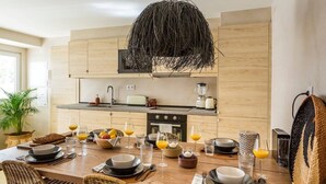 Una cucina moderna con mobili in legno, un'isola centrale con posti a sedere e un lampadario.