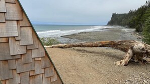 A coastal view with a wooden structure and a fallen tree on a gravel beach. - A-Frame (Site 7) Shelter w/ Incredible Ocean View (Port Angeles)
