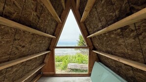 A triangular attic room with a view of a natural landscape.