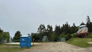 A dirt road leading to a building with a green roof and a blue portable toilet. - A-Frame Site 5 Shelter w/ Incredible Ocean View (Port Angeles)