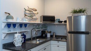 Eine moderne Küche mit weißen Schränken, einem Edelstahl-Kühlschrank, einer Mikrowelle und einem Spülbecken.