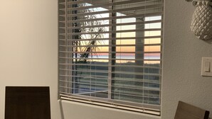 Ein Zimmer mit einem runden Holztisch, einem Fenster mit Jalousien und einem an der Wand montierten Lichtschalter.