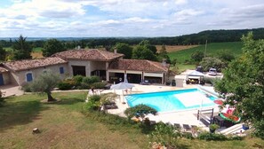 Une maison avec une piscine, un patio couvert et une vue sur la campagne.
