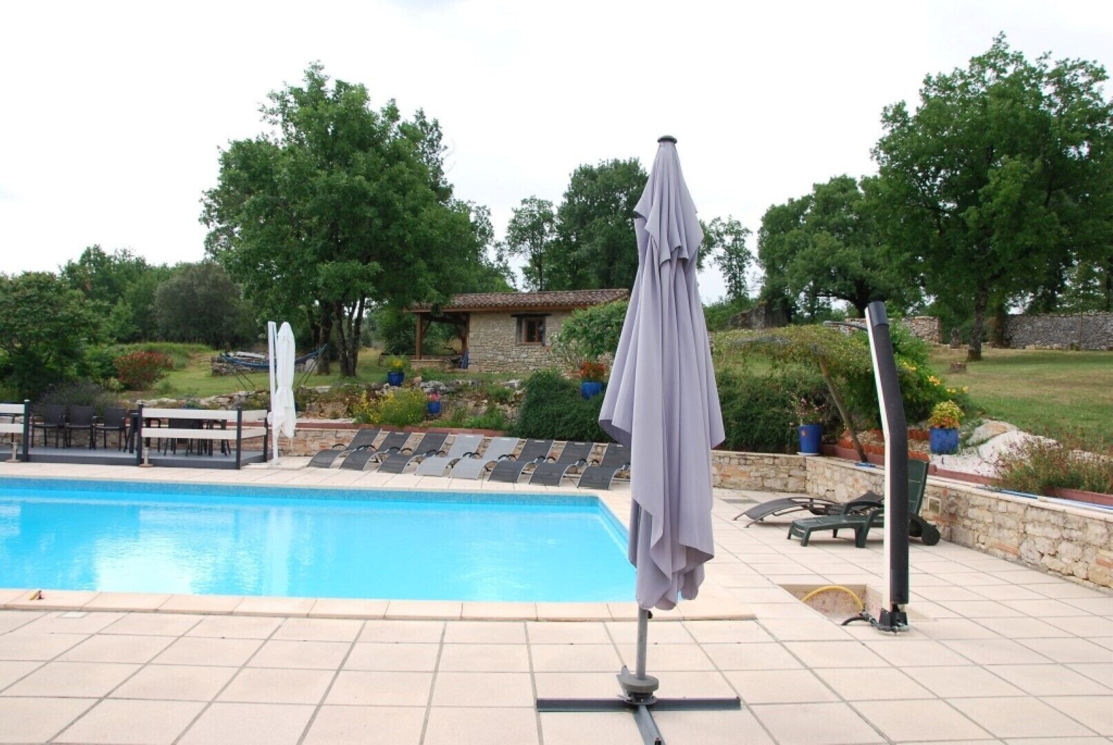 A swimming pool with lounge chairs and a covered umbrella.