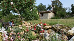A rustic stone house surrounded by a garden with various plants and flowers. - Old stone farmhouse in a quiet location with large heated pool. (lavaurette)