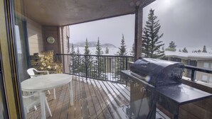 Eine Holzterrasse mit einem Grill, einem weißen Tisch und Stühlen.