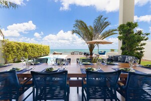 Un área de comedor al aire libre con vista al océano, una piscina y un espacio lounge.