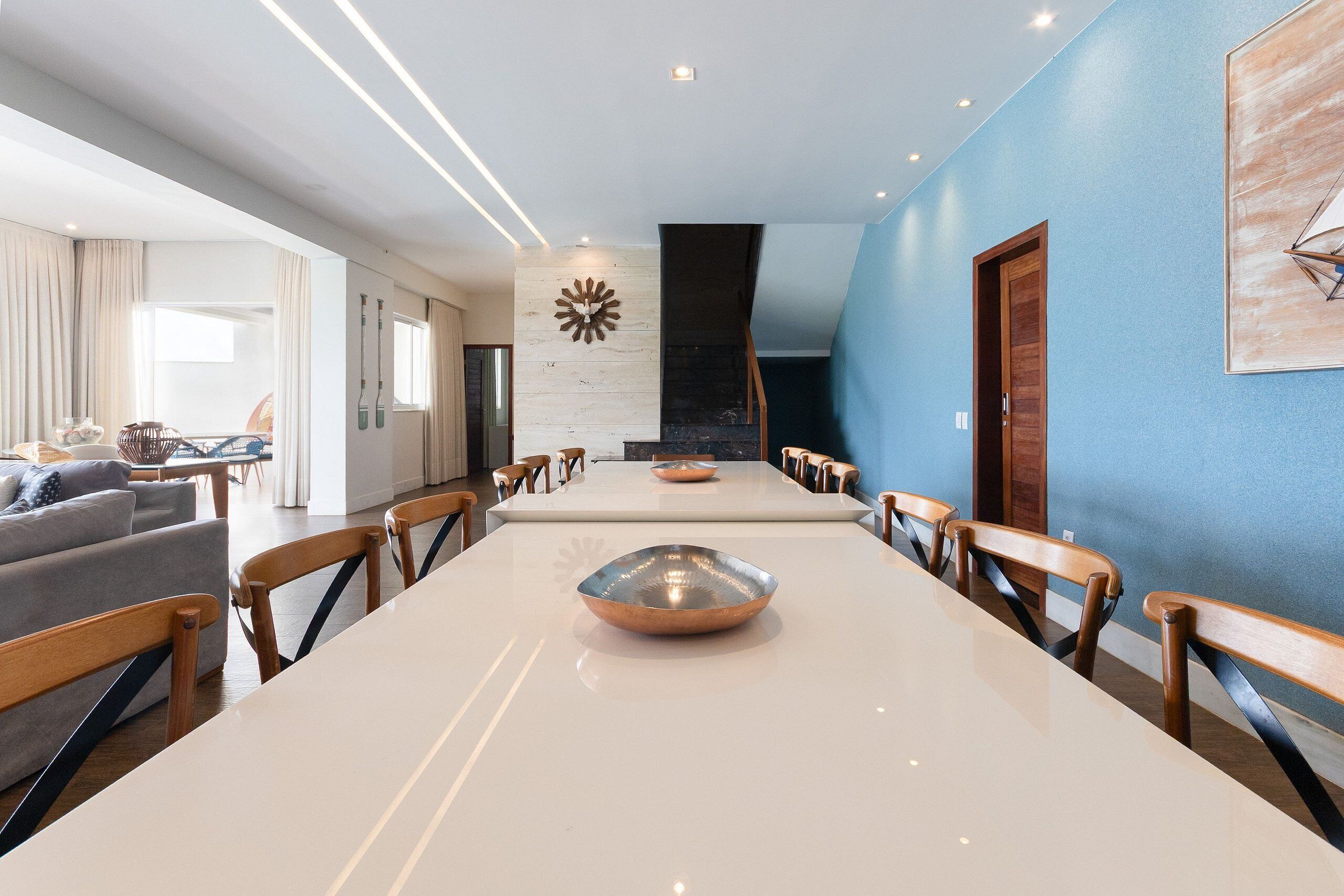 Un comedor moderno con una mesa larga, sillas de madera y un cuenco decorativo en el centro.