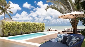 A poolside area with a lounge chair, a table, and an umbrella. - Casa luxuosa a beira mar de Jacumã RN (Ceara-Mirim)