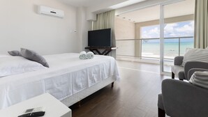 A hotel room with a bed, a TV, a balcony with a view of the ocean, and a chair. - Casa luxuosa a beira mar de Jacumã RN (Ceara-Mirim)