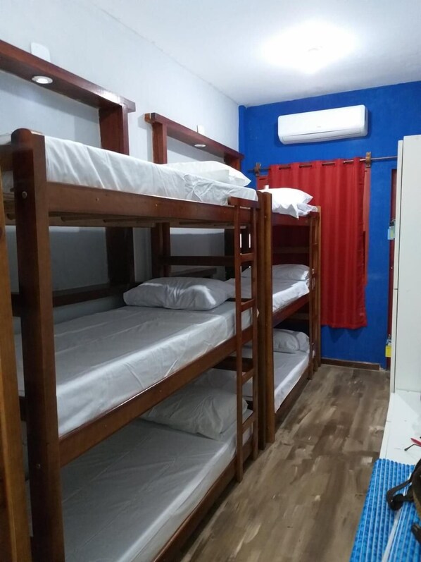 A bunk bed room with a wooden frame, white bedding, a red curtain, and an air conditioning unit on the wall. - Pe Na Areia Beach Hostel (Araruama)