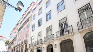 Une rangée de bâtiments blancs dotés de balcons, un lampadaire et des voitures garées.