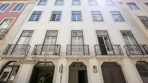 Un immeuble à plusieurs étages, doté d’une façade blanche et portant le numéro 32, abrite au rez-de-chaussée un magasin appelé « TONIRGUY ».