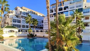 A hotel with a swimming pool, palm trees, and multi-story buildings. - Exclusive pool in apartment area,  5 minutes on foot to beach La Mata (La Mata)