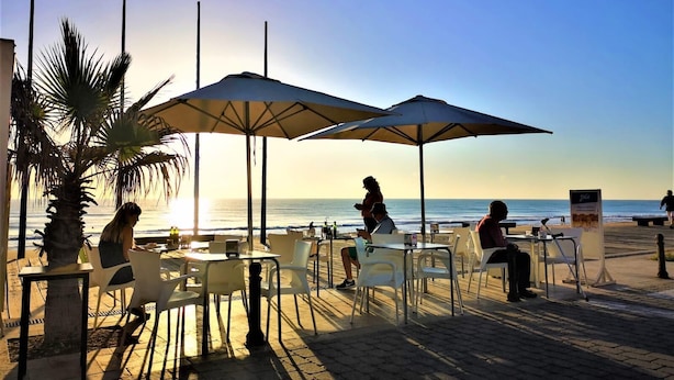An outdoor café with tables and chairs, umbrellas, and a view of the ocean. - Exclusive pool in apartment area,  5 minutes on foot to beach La Mata (La Mata)