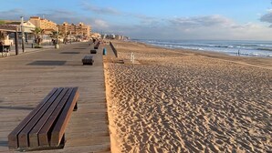A beach with a wooden boardwalk, benches, and a clear view of the ocean. - Exclusive pool in apartment area,  5 minutes on foot to beach La Mata (La Mata)