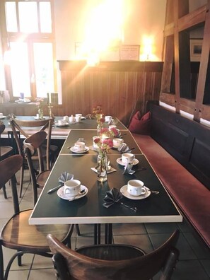 A long dining table set with white cups, saucers, and a vase with flowers. - Restaurant & Hotel Frankenberger (Amt Wachsenburg)