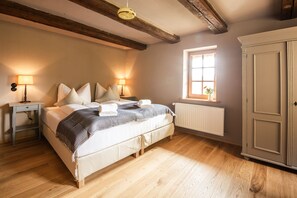 A bedroom with a wooden bed, two bedside tables with lamps, a radiator, and a wardrobe. - Restaurant & Hotel Frankenberger (Amt Wachsenburg)
