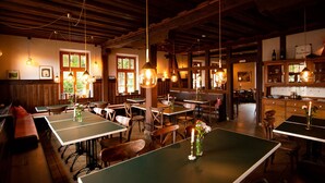 Un restaurant amb taules i caires de fusta, llums penjants i vistes a l'exterior a través de les finestres.