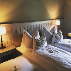 A hotel room with two beds, a nightstand with a lamp, and a headboard with vertical lines.