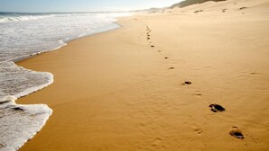 A sandy beach with footprints leading towards the ocean. - Sundowner Loft (Mossel Bay)