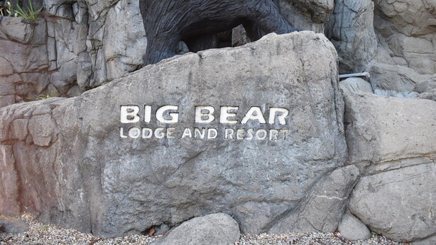 Un grand rocher sur lequel est inscrit « BIG BEAR LODGE AND RESORT » et sur lequel est posée une statue d’ours.