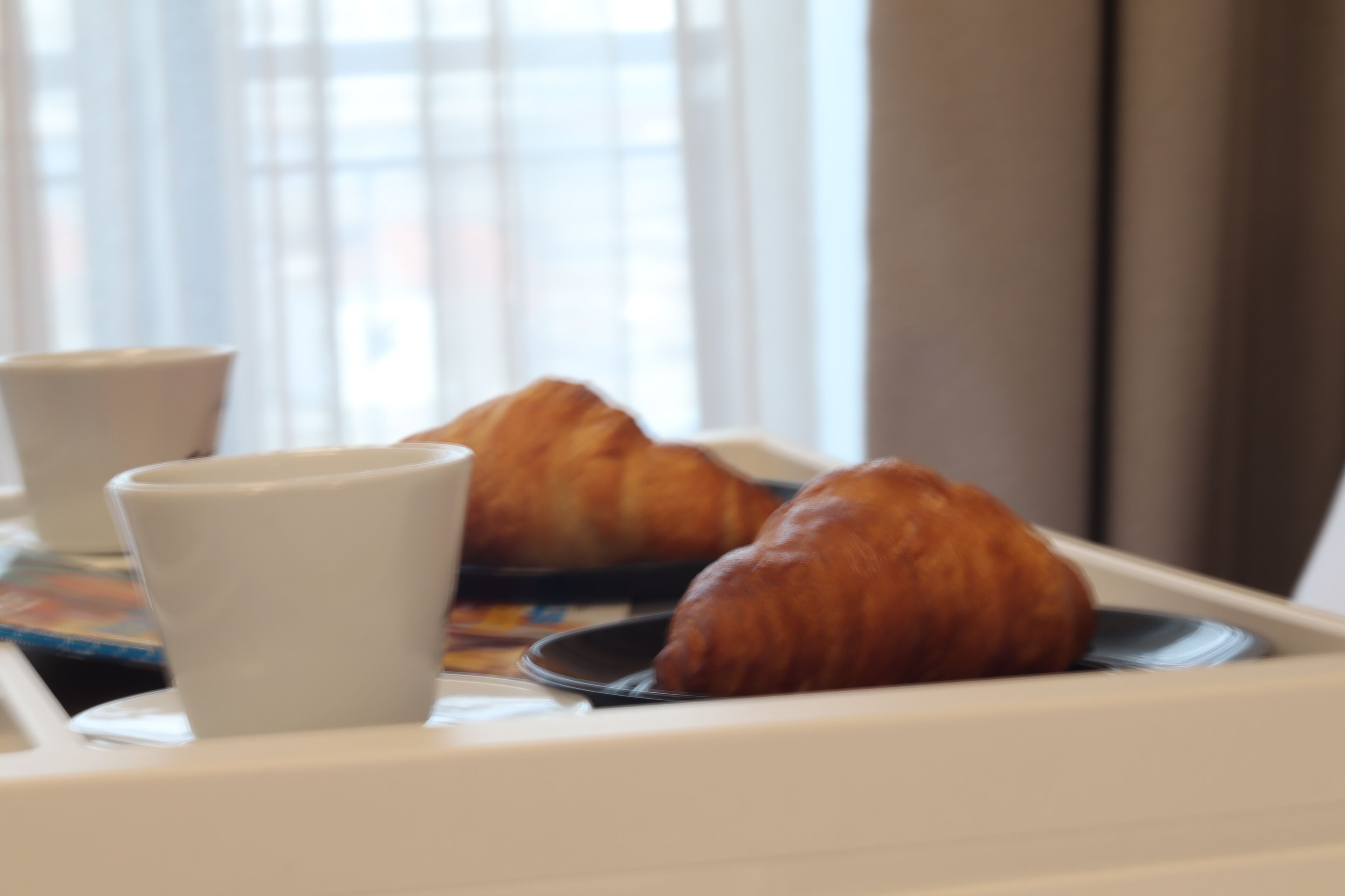 A tray with croissants and a cup, likely in a dining area.