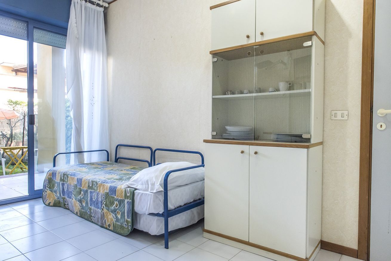 Une chambre à coucher comprenant un lit, une armoire et une porte-fenêtre coulissante donnant sur un espace extérieur.