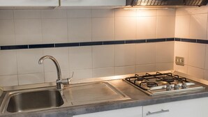 Eine Küche mit Spüle aus Edelstahl, einem Gasherd und weißen Schränken.
