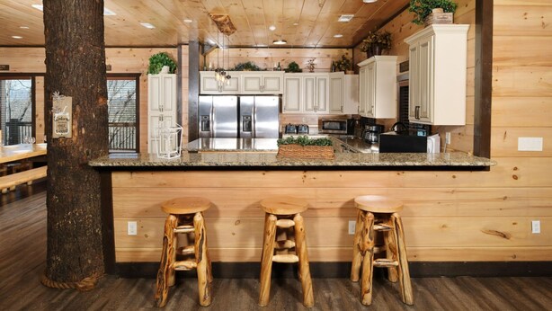 A kitchen with wooden cabinets, stainless steel appliances, and a central island with stools.