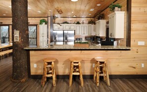 Une cuisine dotée de meubles en bois, d’appareils électroménagers en acier inoxydable et d’un îlot central avec des tabourets.