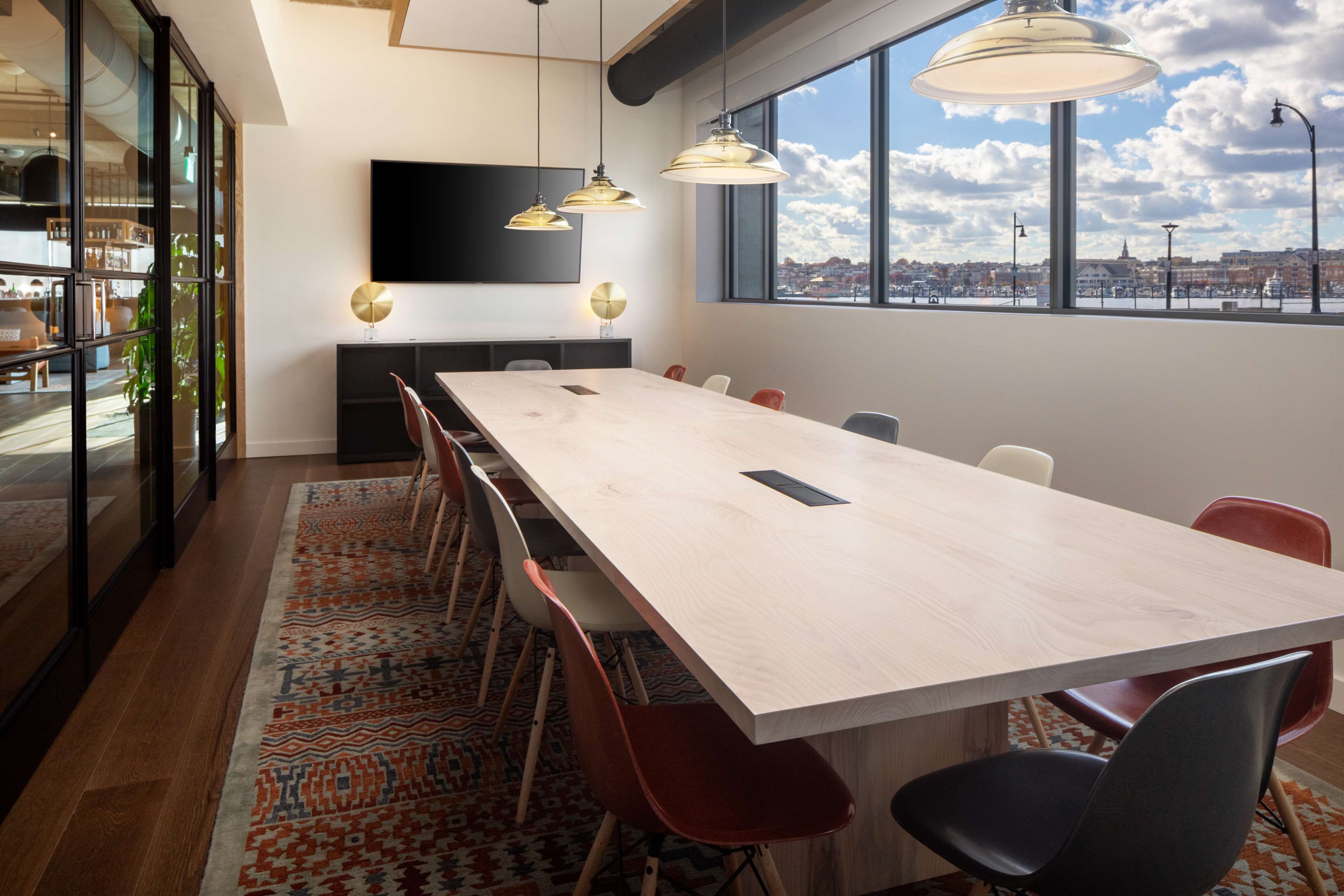 A conference room with a long table, modern chairs, and pendant lighting.