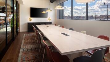 A conference room with a long table, modern chairs, and pendant lighting.