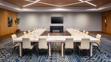A conference room with a long table, multiple chairs, a flat-screen TV, and a fireplace.