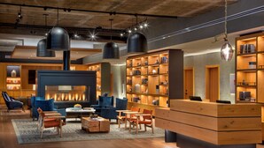 A modern lobby with a fireplace, seating area, and wooden bookshelves. - Canopy by Hilton Baltimore Harbor Point (Baltimore)