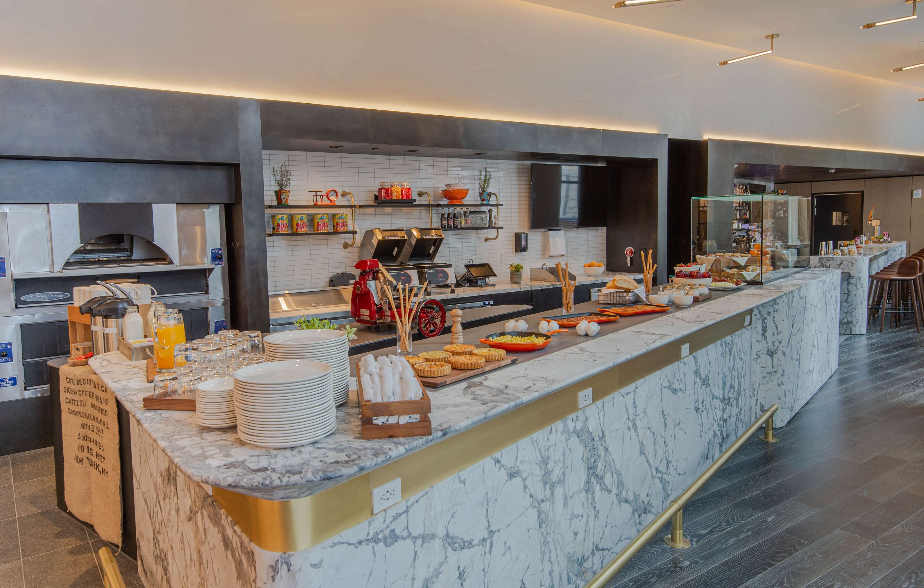 A modern breakfast bar with a marble countertop, a coffee machine, and various breakfast items.