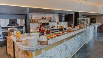 A modern breakfast bar with a marble countertop, a coffee machine, and various breakfast items.