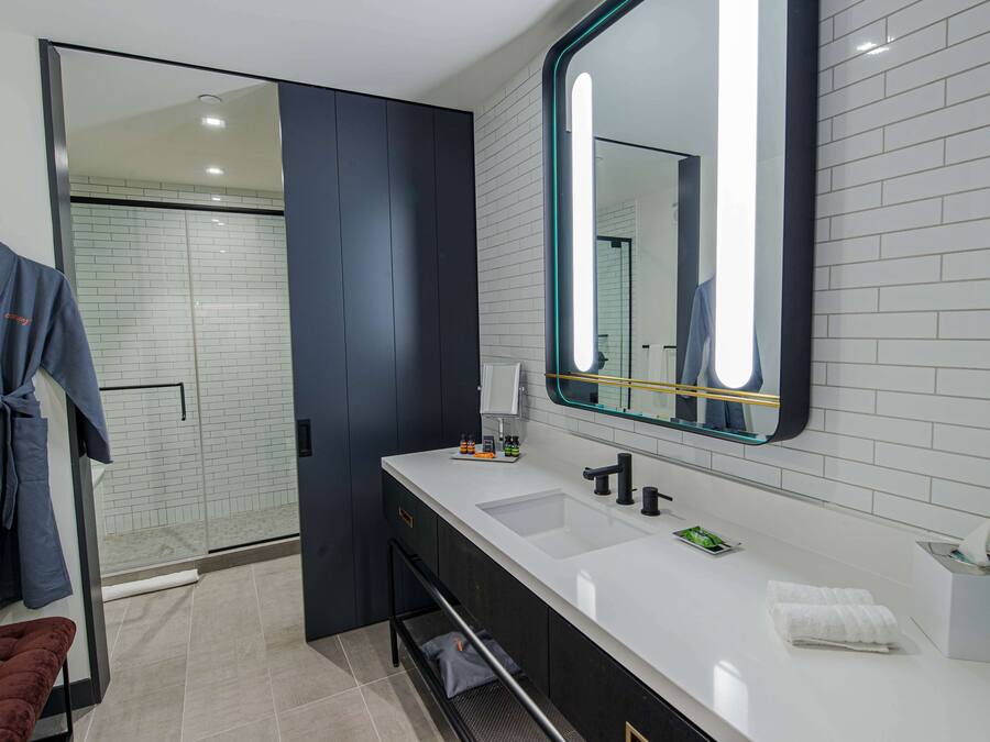 Un baño moderno con un espejo grande, dos lavamanos y una ducha a ras de suelo.