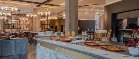 A modern breakfast bar with marble countertops, a coffee station, and a seating area with chairs and tables.