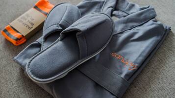 A pair of grey slippers and a folded grey garment with orange text on the side.