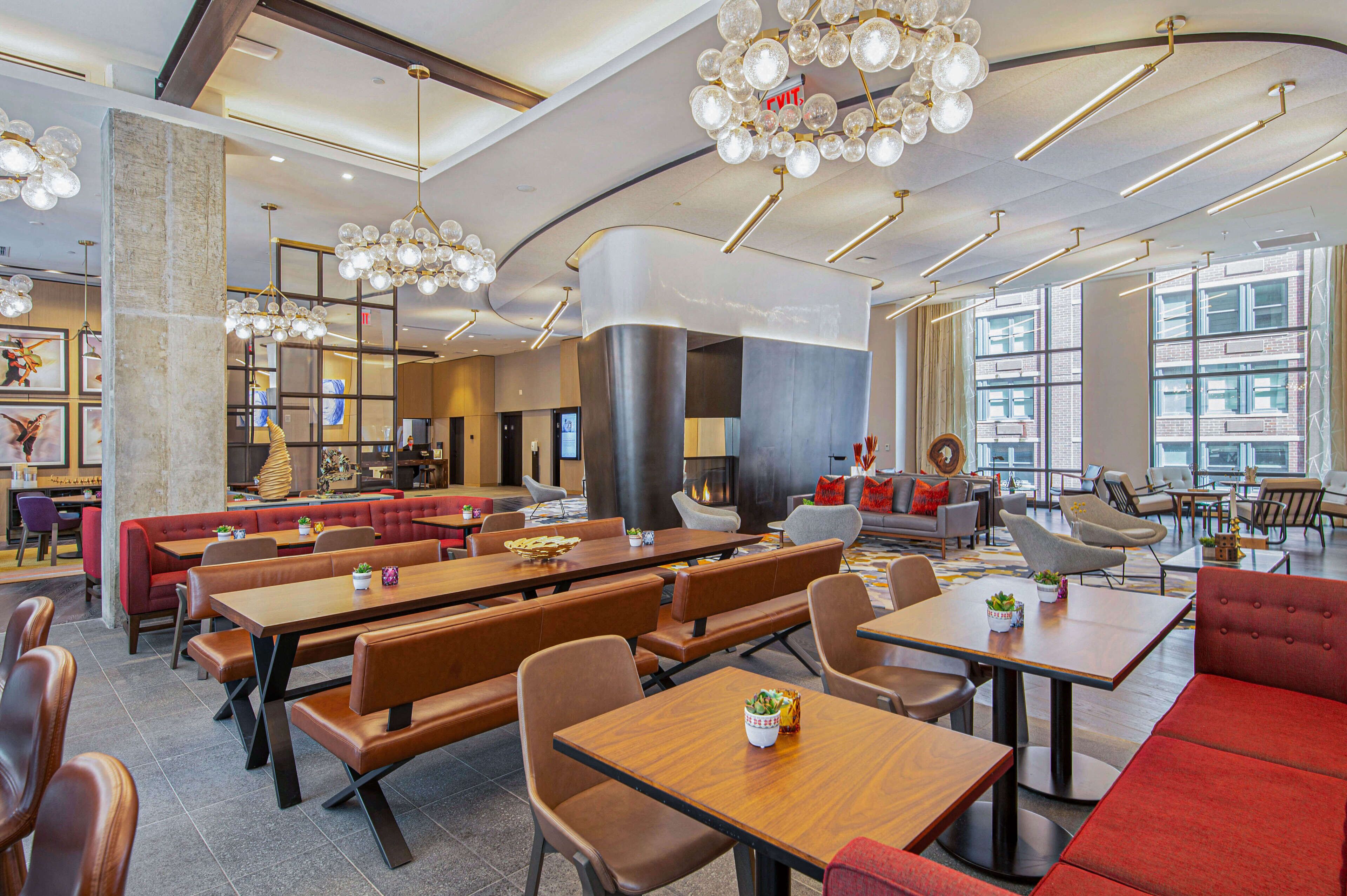 A modern restaurant with high ceilings, pendant lighting, and a mix of seating options including booths and tables.