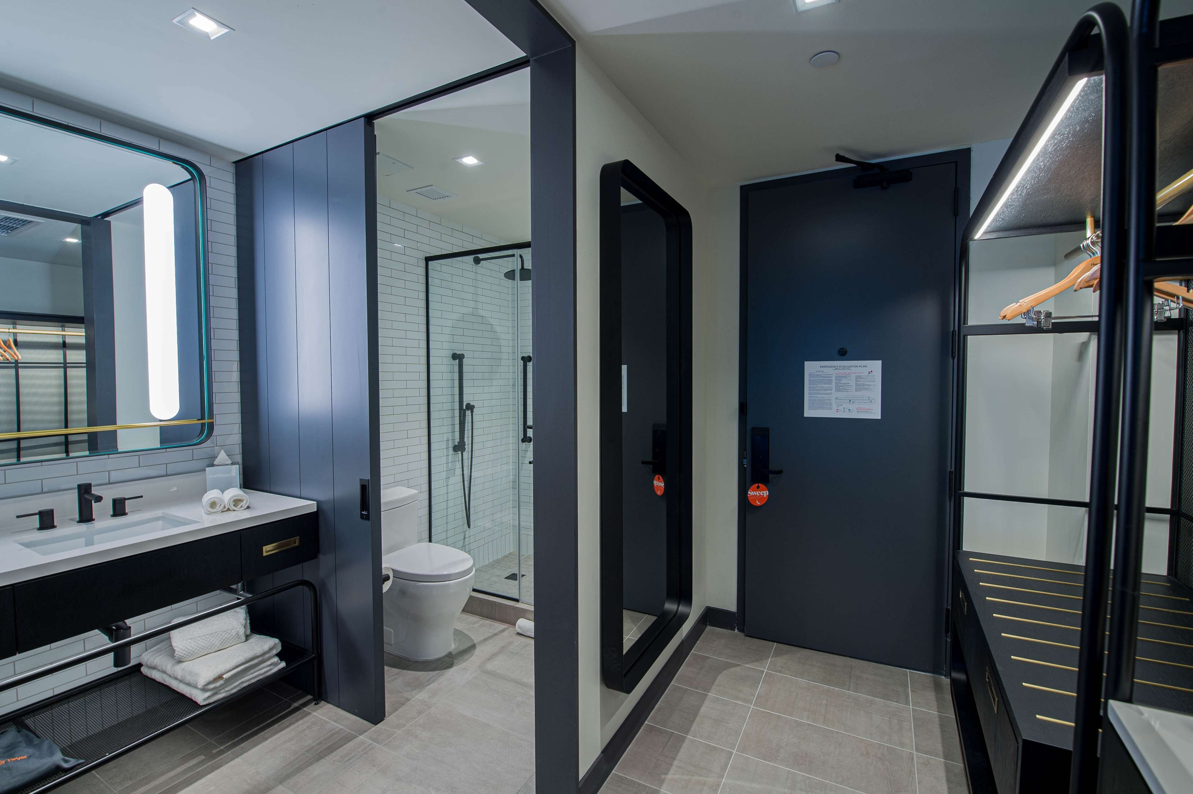 A modern bathroom with a large mirror, a sink, a toilet, and a shower area.