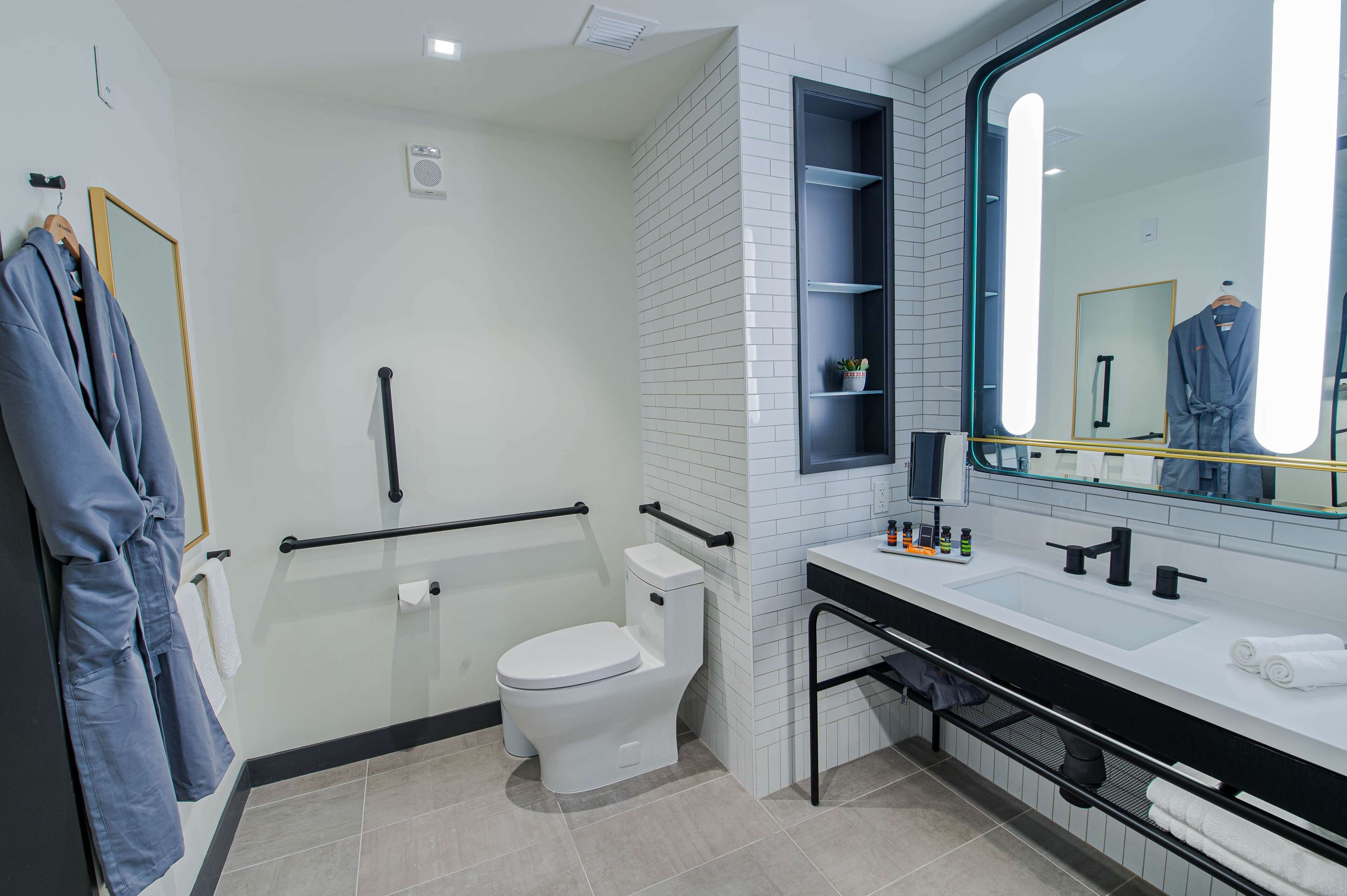 A modern bathroom with a white toilet, a large mirror, and a black sink.